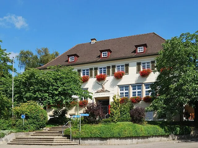 Charmantes Verwaltungsgebäude in Rosenberg, Ostalbkreis, mit blühenden Blumenkästen und gepflegtem Garten.