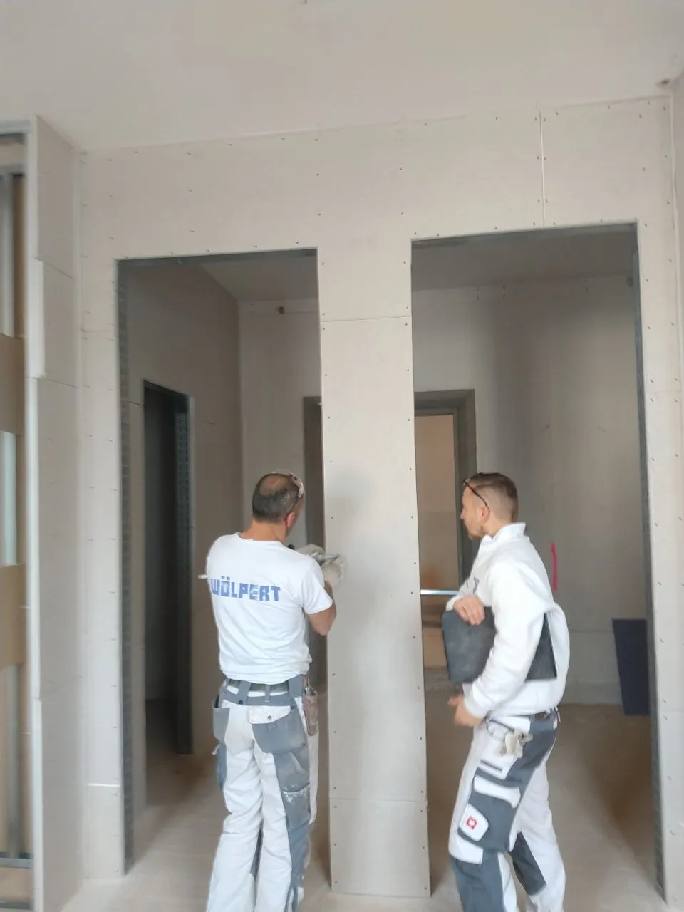 Trockenbauarbeiten in Ellenberg: Zwei Bauarbeiter planen eine Innenwand mit Trockenbauplatten. Professionelle Trockenbaudienstleistungen in Neuler und Umgebung.